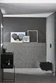 Schwarze Waschtischarmatur von Ideal Standard an einem schwarzen Waschtisch mit geometrischem Fliesenmuster und Kunstwerken an der Wand in modernem Badezimmer.
